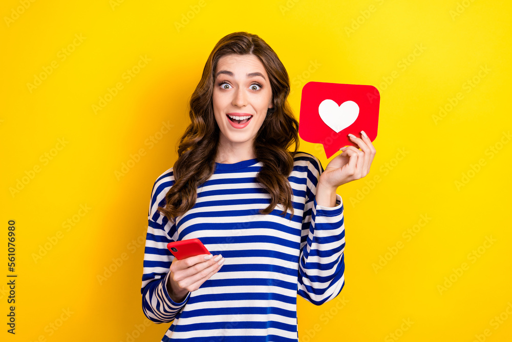 Photo of young overjoyed excited satisfied lady brown curly hair hold red paper like notification with phone isolated on yellow color background Photo of young overjoyed excited satisfied lady brown curly hair hold red paper like notification with phone isolated on yellow color background