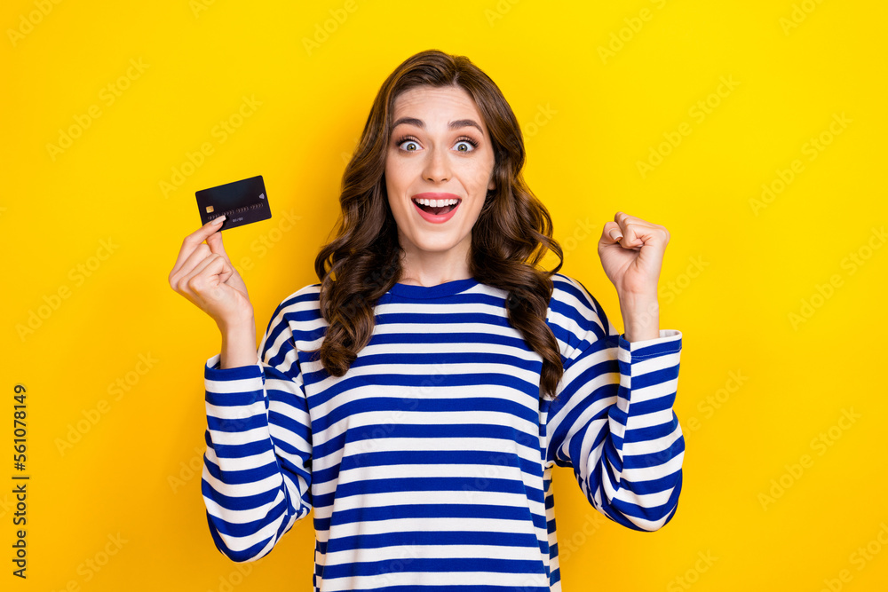 Photo of delighted person toothy smile hand hold debit card raise fist celebrate isolated on yellow color background