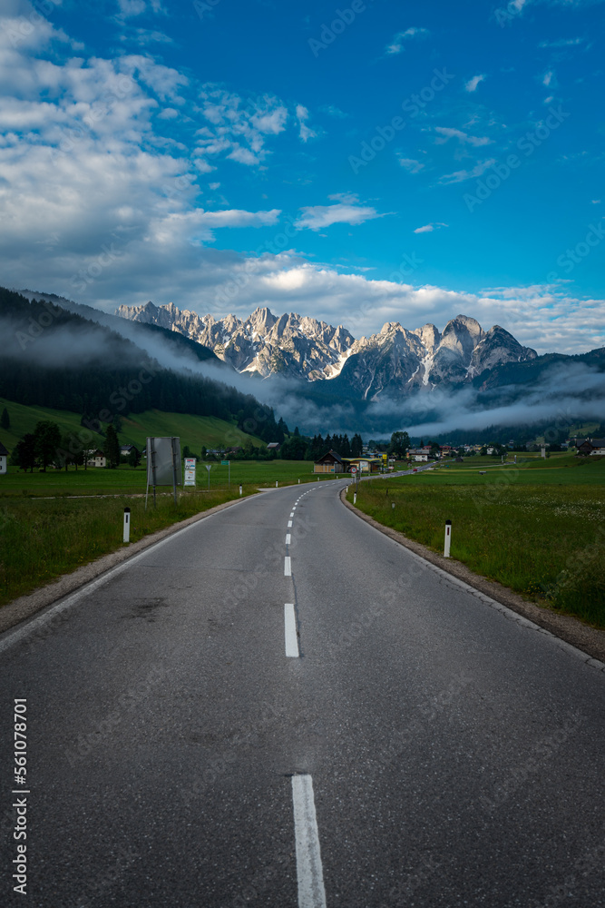 Straße in den Alpen mit Bergen, Wolken, grünen Wiesen und blauem Himmel. Straße in den Alpen mit Bergen, Wolken, grünen Wiesen und blauem Himmel.