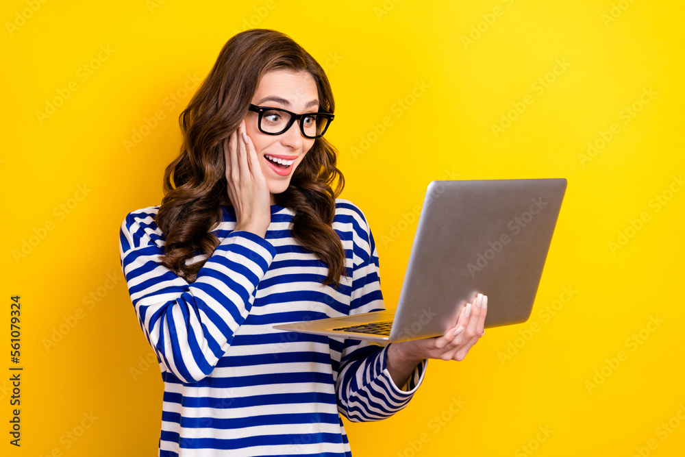 Photo of excited shocked businesswoman curly hair touch cheek surprised watch computer crazy financial results isolated on yellow color background
