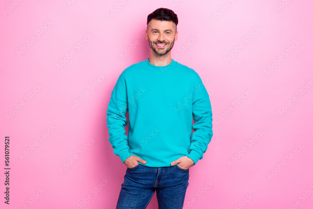 Fototapeta premium Photo of young cheerful satisfied guy wear blue jumper hands pockets successful entrepreneur smiling enjoy his job isolated on pink color background