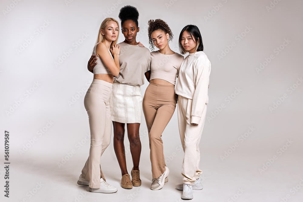 beauty portrait of diverse women, caucasian, asian and african american ladies with different skintone posing at camera, hugging each other, dressed casually in beige tone clothes. isolated beauty portrait of diverse women, caucasian, asian and african american ladies with different skintone posing at camera, hugging each other, dressed casually in beige tone clothes. isolated