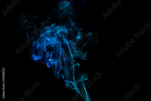 incense stick with blue smoke against black background