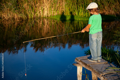 Boy fisherman with a fishing rod on the shore of the lake, child vacations. Happy boy go fishing on the river. © Chepko Danil
