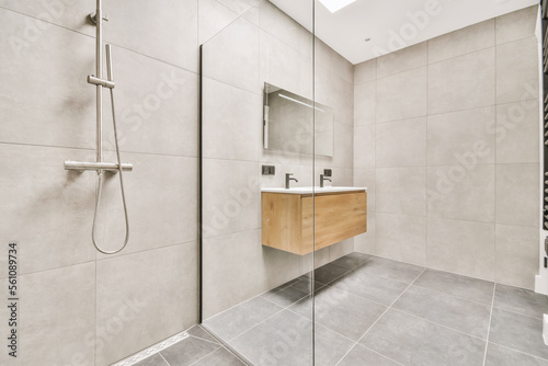 a modern bathroom with grey tile flooring and wall mounted shower fauced in the corner of the room photo