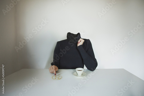 headless surreal woman draws a sad face on the table with coffee, concept of communicating one's mood