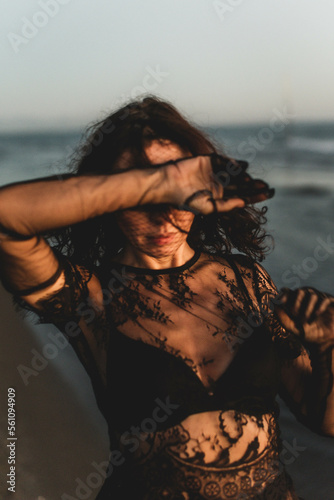Portrait woman in sexy black dress walking with on the winter beach