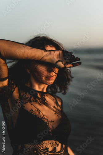 Portrait woman in sexy black dress walking with on the winter beach