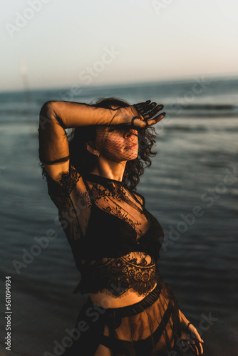 Portrait woman in sexy black dress walking with on the winter beach