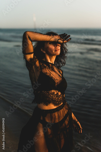 Portrait woman in sexy black dress walking with on the winter beach