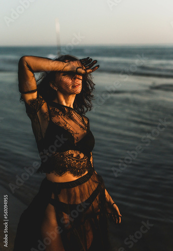 Portrait woman in sexy black dress walking with on the winter beach