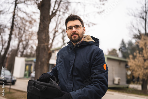 One bearded caucasian man with laptop bag standing outdoor in winter