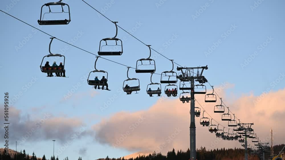 Skiers and snowboarders take the lift to the next skiing from the snowy slope Skiers and snowboarders take the lift to the next skiing from the snowy slope