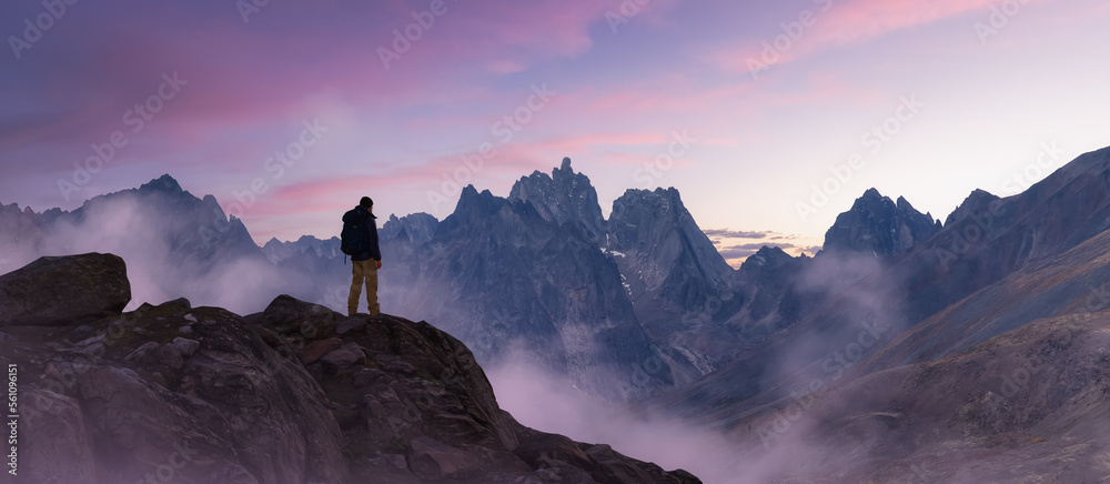 Φωτογραφία Adventurous Man Hiker standing on top of peak with rocky mountain in background