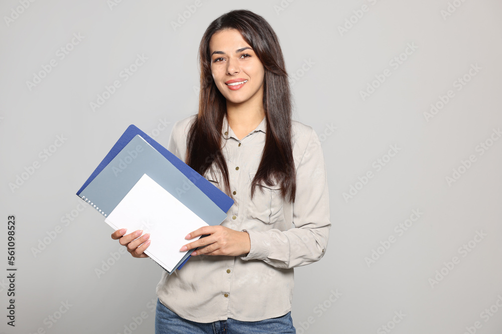 Happy young teacher with books on light grey background. Space for text Happy young teacher with books on light grey background. Space for text