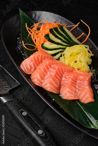 Chefs knife and served salmon sashimi on black background