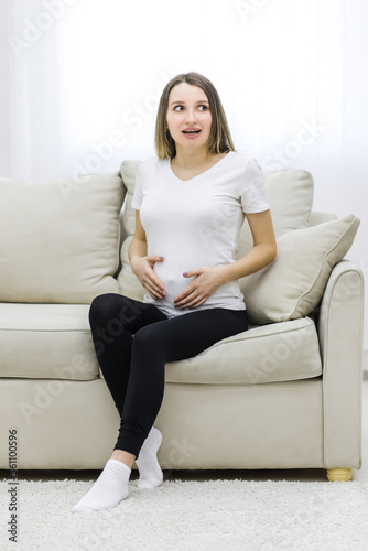Pregnant woman sitting on white sofa. Concept of pregnant woman