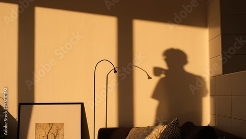 shadow on the wall from a man drinking tea