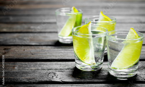 Vodka with lime slices in a shot glass.