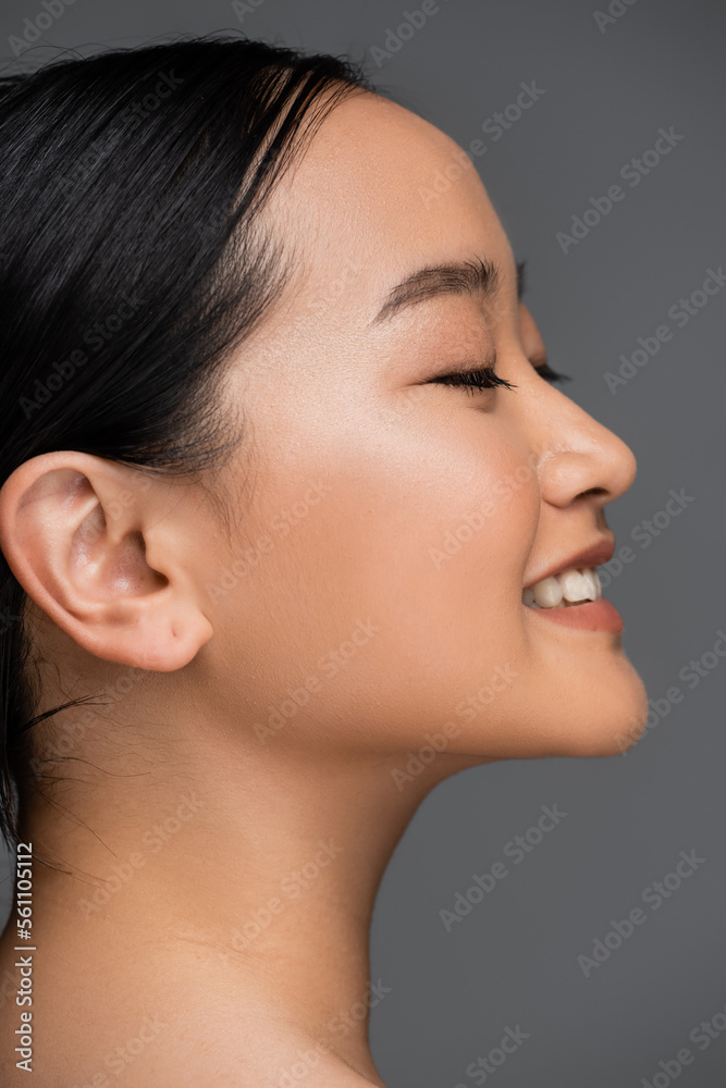 Side view of smiling asian woman closing eyes isolated on grey. Side view of smiling asian woman closing eyes isolated on grey.