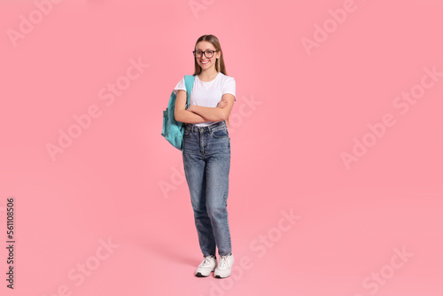 Teenage girl with backpack on pink background