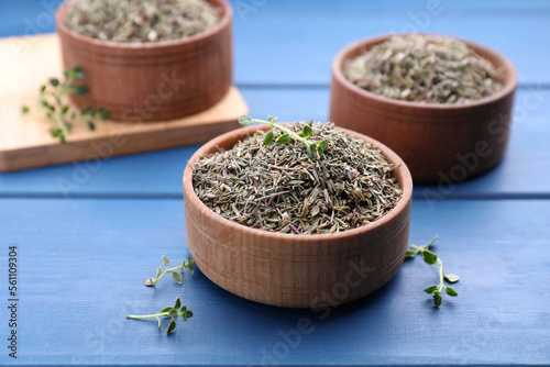 Bowls with dried and fresh thyme on blue wooden table  closeup