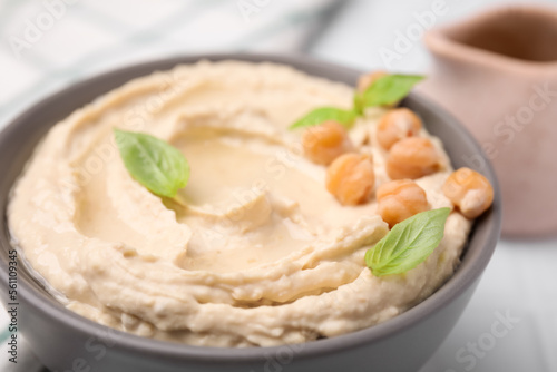 Delicious hummus with chickpeas served on white tiled table, closeup