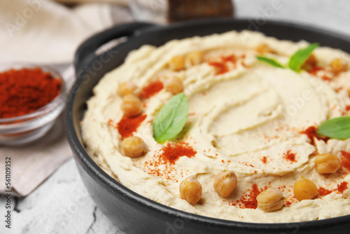 Delicious hummus with chickpeas and paprika served on white textured table, closeup
