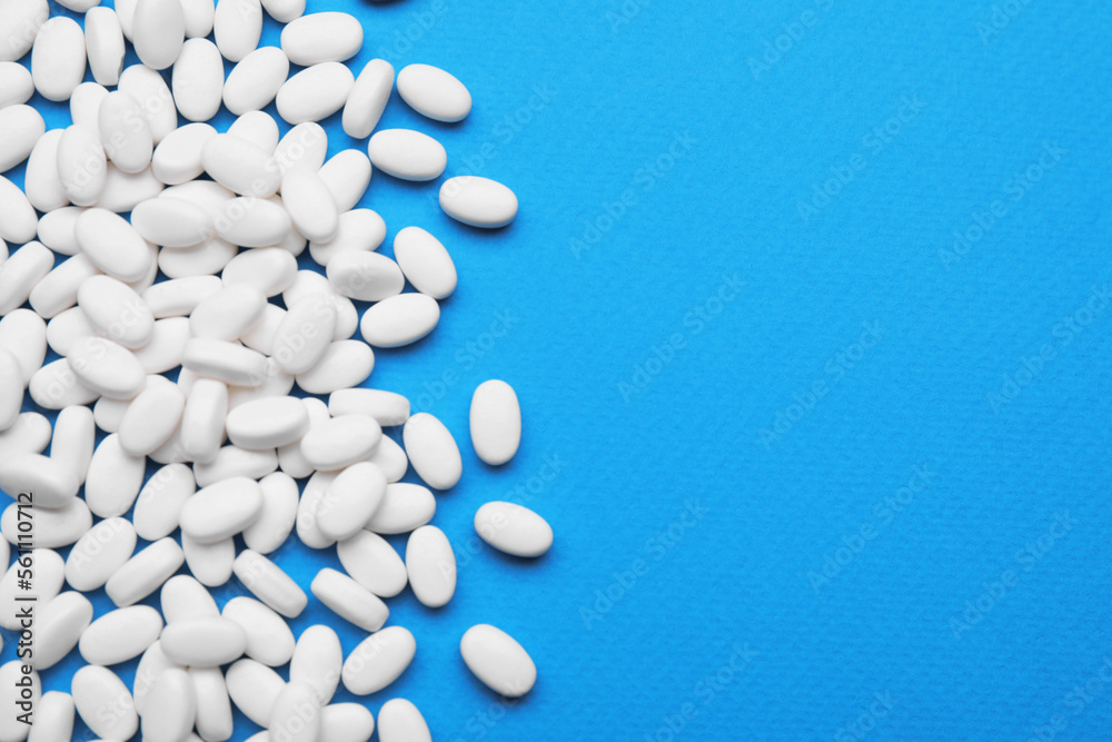 Many dragee candies on blue background, flat lay. Space for text