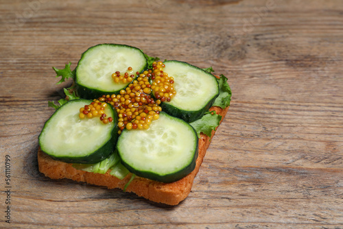 Tasty cucumber sandwich with arugula and mustard on wooden table