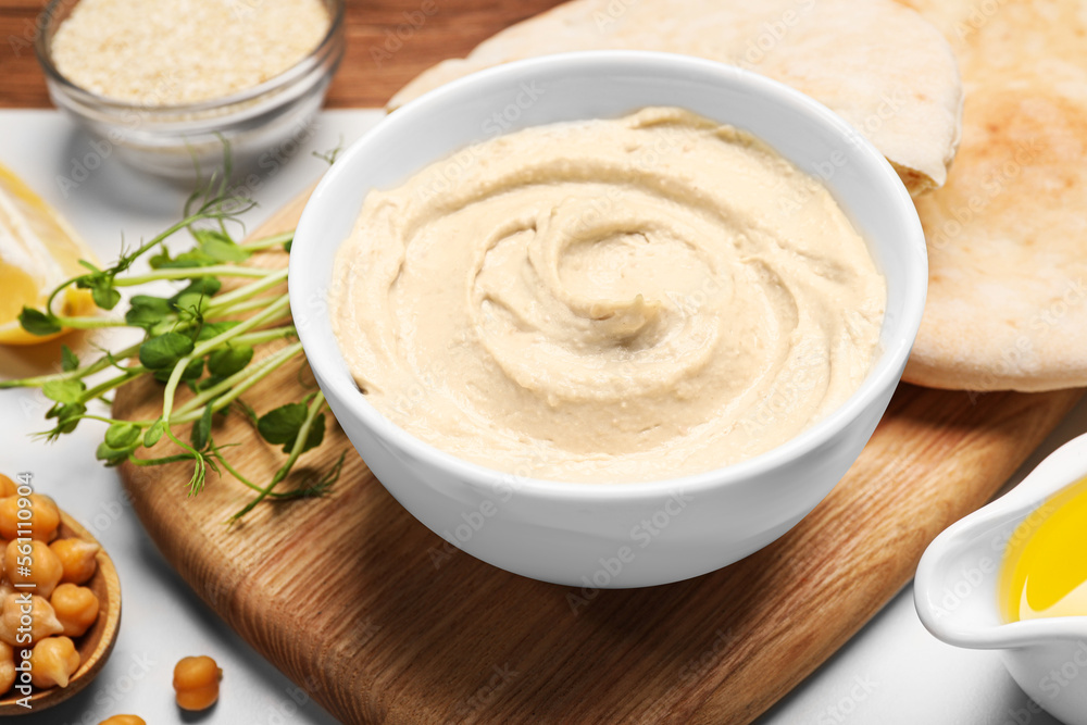 Delicious hummus and different ingredients on white table Delicious hummus and different ingredients on white table