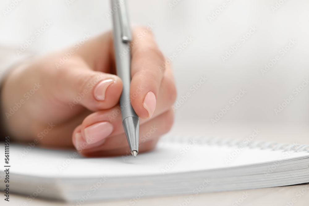 Woman writing with pen in notebook, closeup Woman writing with pen in notebook, closeup