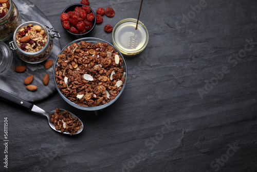 Fototapeta Naklejka Na Ścianę i Meble -  Tasty granola served with nuts and dry fruits on black table, flat lay. Space for text
