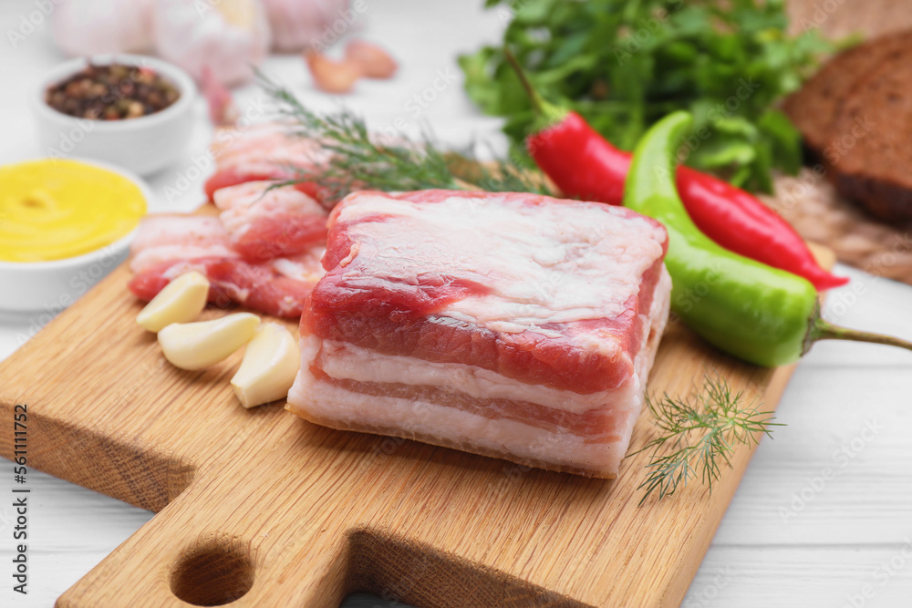 Pieces of tasty pork fatback with garlic and chilli pepper on white table Pieces of tasty pork fatback with garlic and chilli pepper on white table