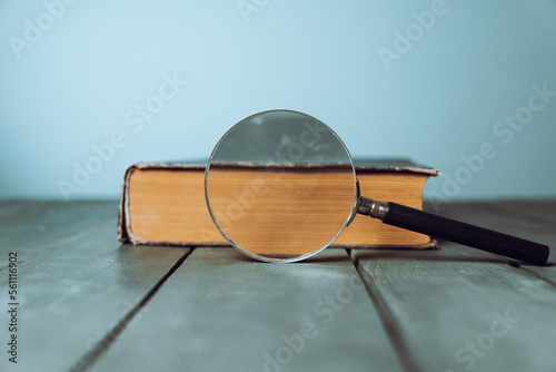 Book and magnifier on wooden table