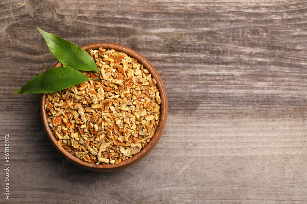 Bowl of dried orange zest seasoning and fresh leaves on wooden table, top view. Space for text Bowl of dried orange zest seasoning and fresh leaves on wooden table, top view. Space for text