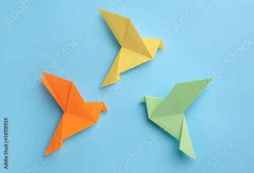 Origami art. Colorful handmade paper birds on light blue background  flat lay