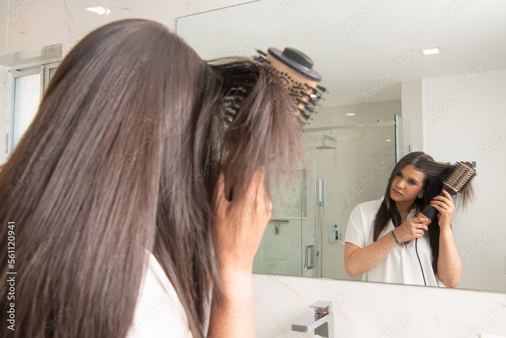 latin woman in front of a mirror styling her hair