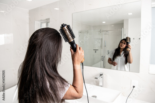 Obraz na płótnie Girl looking at the mirror using a hair dryer brush w salonie