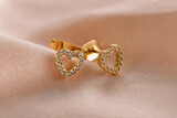 Hearts shape gold stud earrings  with diamonds on pink background. Romantic jewelry. Сoncept for Valentine's Day