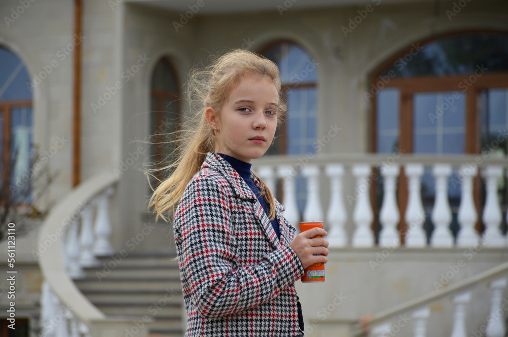 a beautiful girl in a plaid coat on a walk in the autumn park against the backdrop of a vintage building, holding a can of drink in her hand. quench your thirst in the fresh air. active lifestyle a beautiful girl in a plaid coat on a walk in the autumn park against the backdrop of a vintage building, holding a can of drink in her hand. quench your thirst in the fresh air. active lifestyle