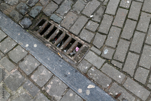 Cobbled street with cigarette butts and drain - Brussels - Belgium