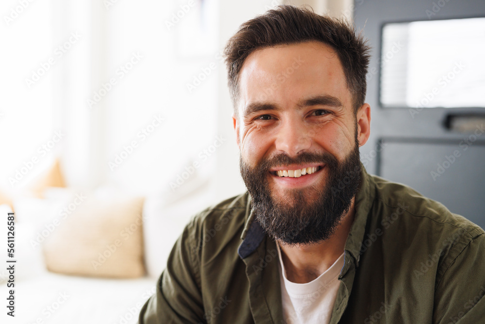 Close-up portrait of bearded biracial smiling young man wearing jacket in living room, copy space Close-up portrait of bearded biracial smiling young man wearing jacket in living room, copy space