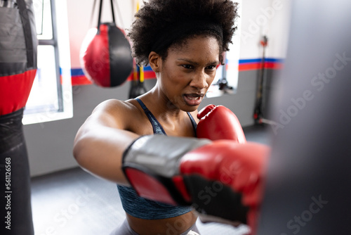 African american fit woman exercising and punching boxing bag at gym photo