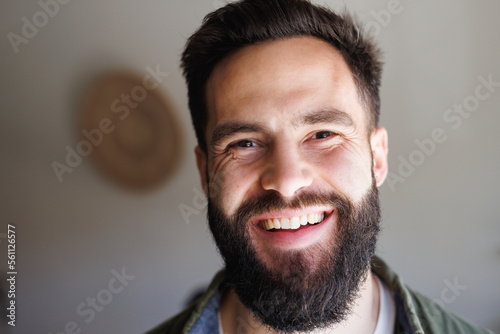 Close-up portrait of handsome bearded biracial young man smiling against white wall, copy space