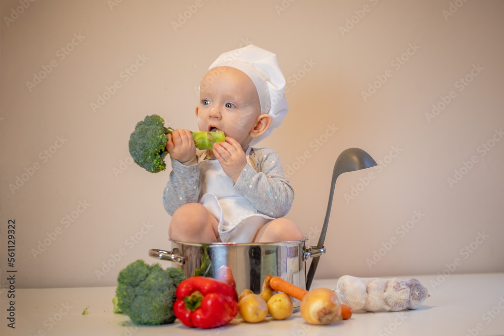 Little female chef preparing vegetable soup in kitchen.