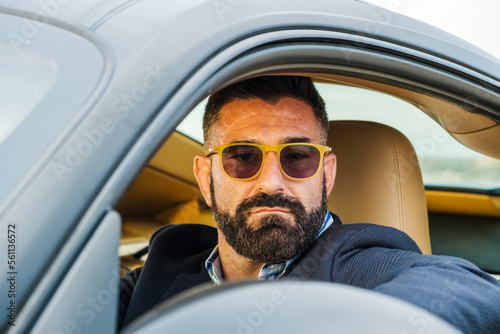 Bearded man in sun glasses drives his car