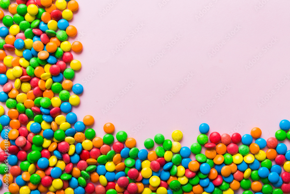 Obraz premium Mixed collection of colorful candy, on colored background. Flat lay, top view. frame of colorful chocolate coated candy
