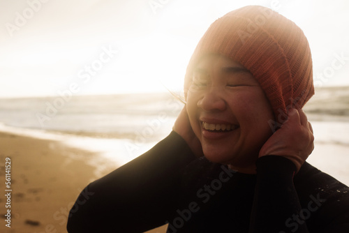 beautiful Asian woman holding her hat ready for cold water swimming
