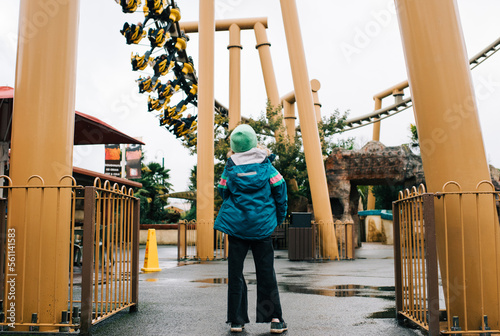 child looking up at a rollercoaster ride in an amusement park photo